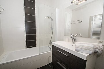 A bathroom with black and white tiles and a sink