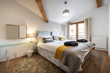 A bedroom with a large bed and a mirror