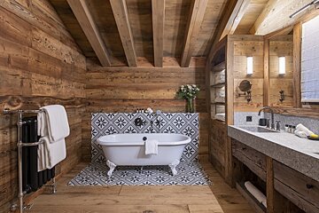 A bathroom with wooden walls and a white bathtub