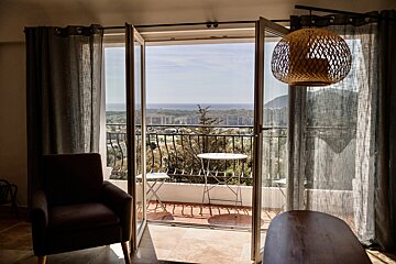 A balcony with a view of the ocean and mountains
