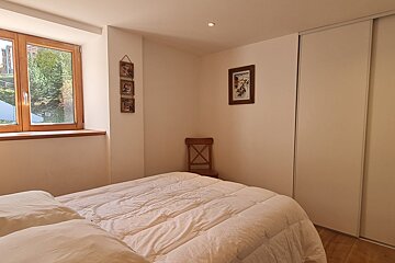 A bedroom with a bed a chair and a window