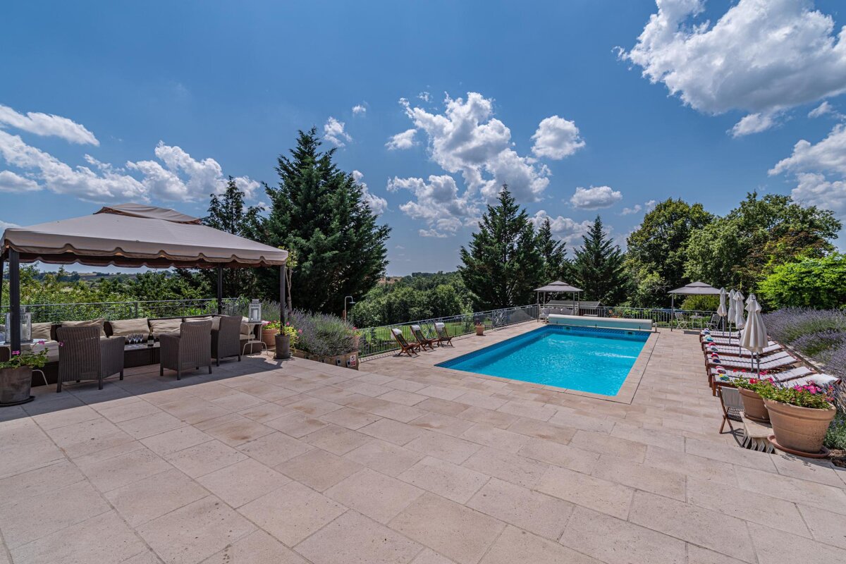 A large swimming pool surrounded by chairs and umbrellas