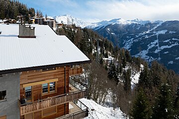 A snowy mountain landscape with a house in the foreground