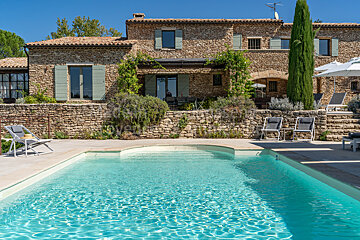 A large stone house with a swimming pool in front of it