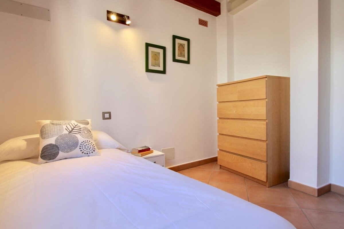 A bedroom with a dresser and a pillow on the bed