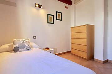 A bedroom with a dresser and a pillow on the bed