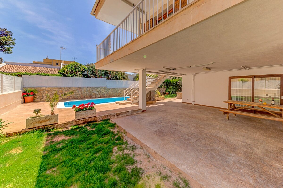 The backyard of a house with a swimming pool and a picnic table