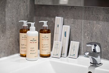 Two bottles of nuxe lotion sit on a bathroom sink