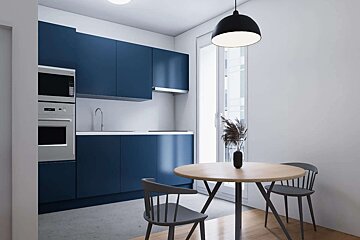 A modern kitchen featuring navy blue cabinets, stainless steel appliances, and a light wood dining table with dark chairs. White walls, a large window, and a black pendant light complete the scene.