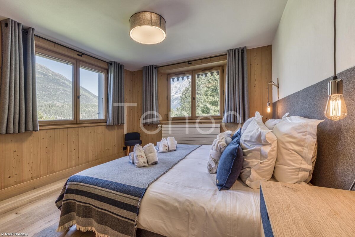 A bedroom with a large bed and a large window with the word tenda on the wall