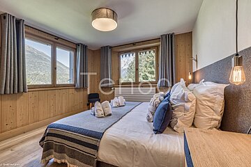 A bedroom with a large bed and a large window with the word tenda on the wall