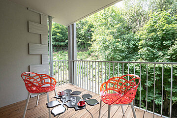 A balcony with two red chairs and a table