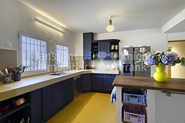A kitchen with blue cabinets and a yellow floor has the word frank on the wall