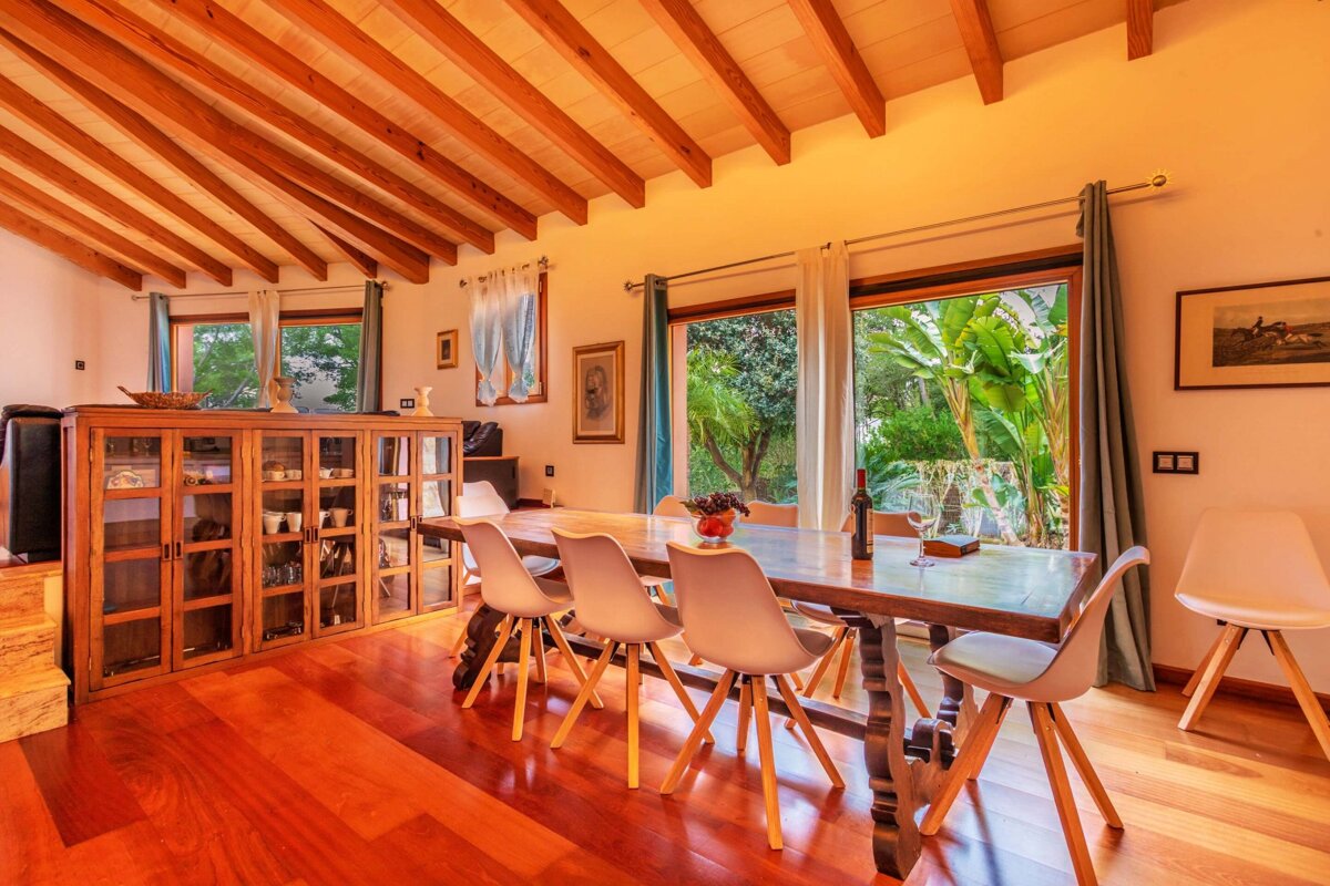 A dining room with a long wooden table and white chairs