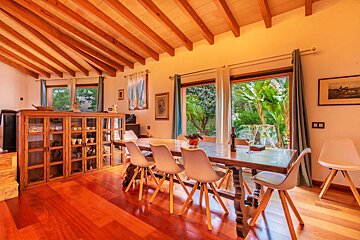 A dining room with a long wooden table and white chairs
