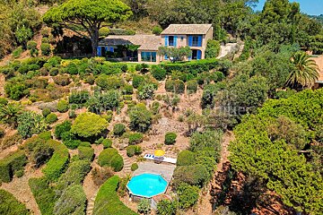 An aerial view of a house surrounded by trees and bushes