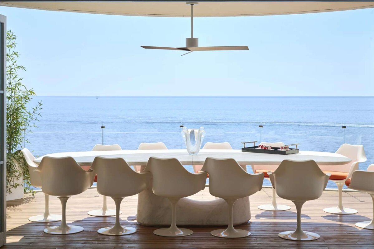 A dining room with a table and chairs overlooking the ocean