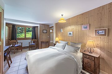 A bedroom with two beds a chair and a television