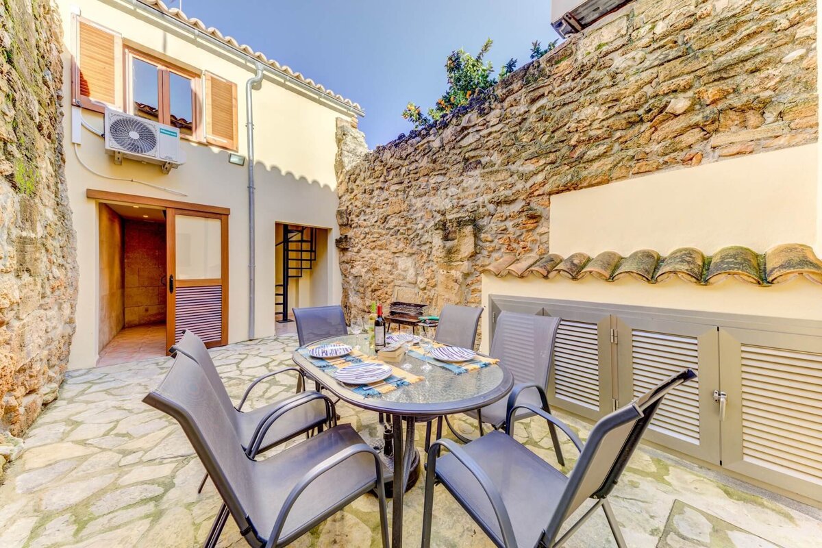 A patio with a table and chairs in front of a stone wall