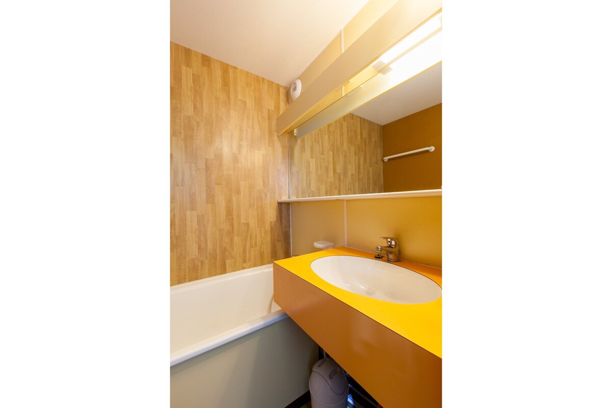 A bathroom with a yellow sink and a bathtub