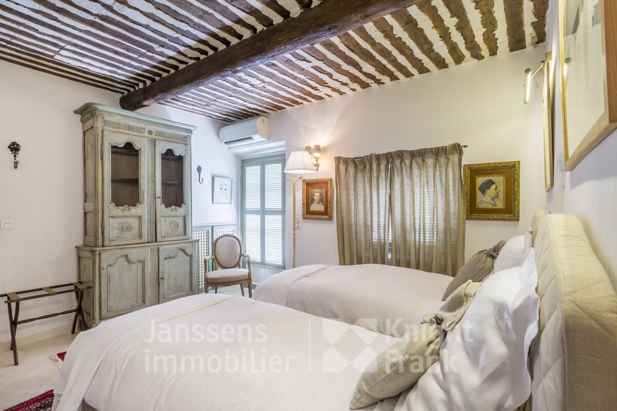 A bedroom with two beds and a cabinet that says janssens immobilier on it