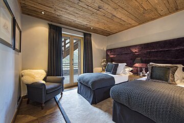 A bedroom with two beds and a chair