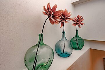 Three vases with flowers in them on a shelf
