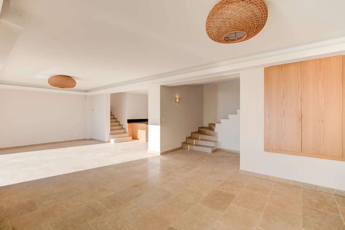 An empty room with a wicker lamp hanging from the ceiling