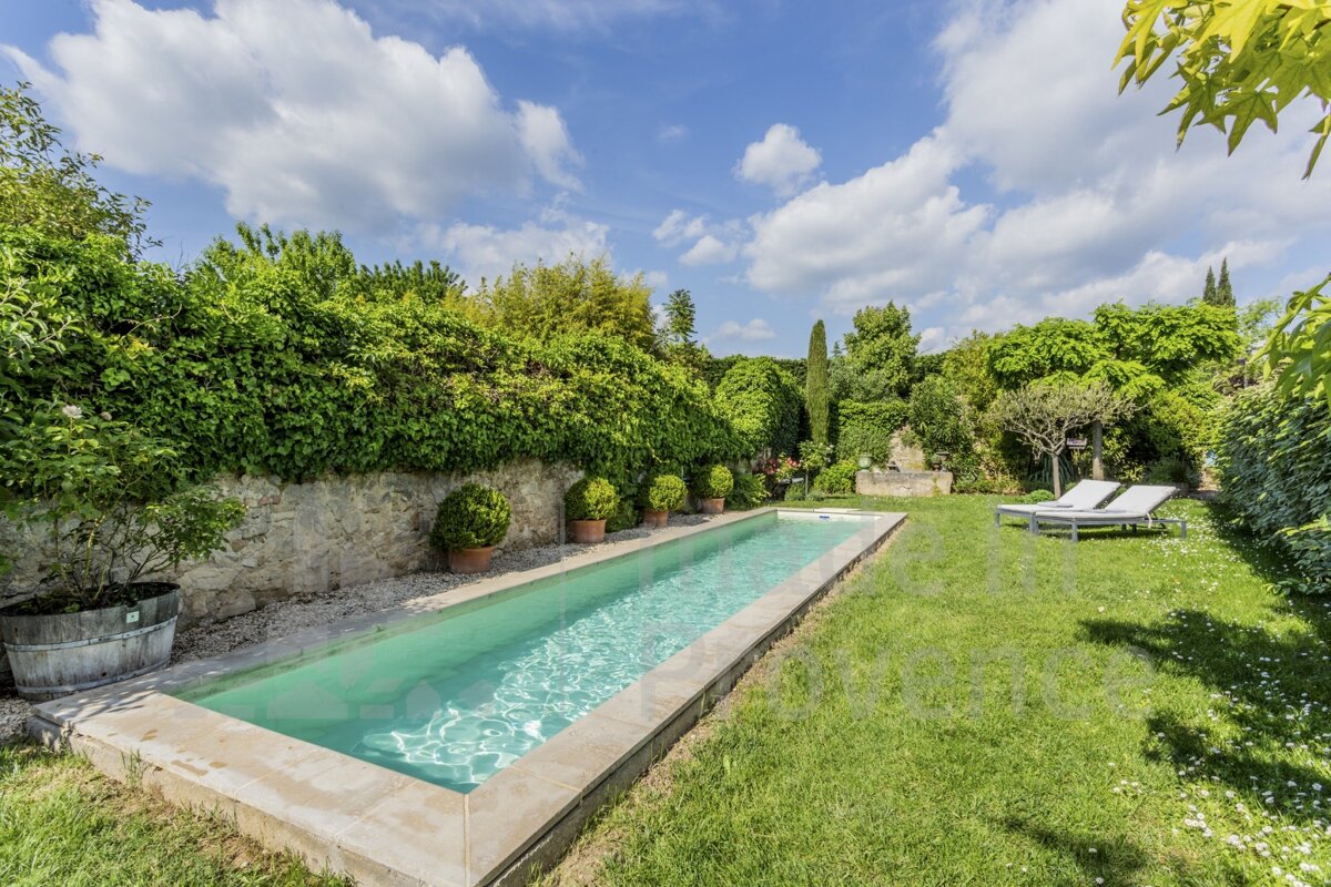A large swimming pool is surrounded by lush greenery