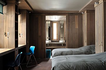 A bedroom with two beds and a blue chair