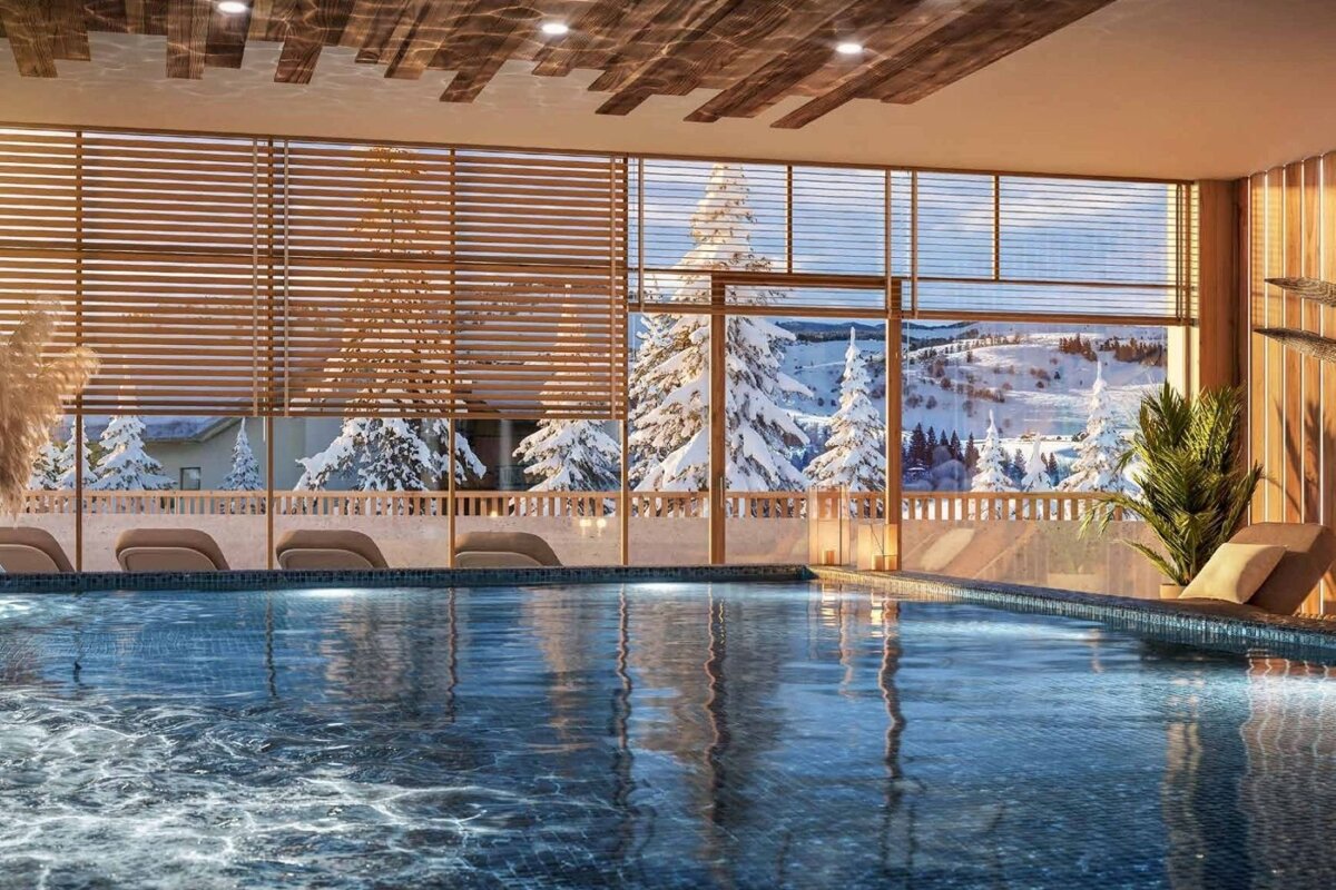 An indoor pool with large windows offering a scenic view of a snowy mountain landscape.