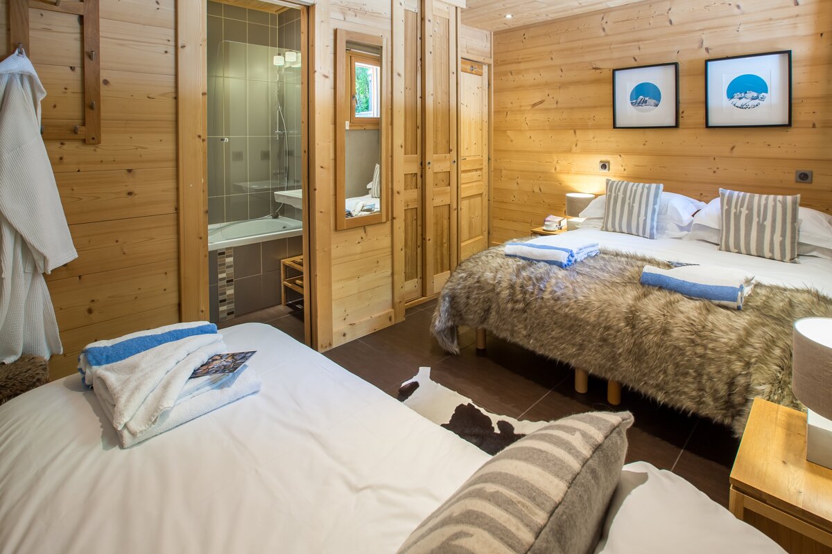 A bedroom with two beds and a bathroom