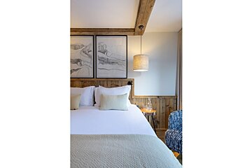 A bedroom with a bed and two paintings on the wall