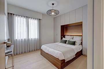 A bedroom with a bed and a window with white curtains