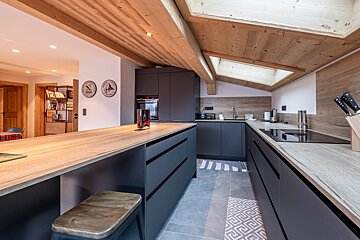 A kitchen with a clock on the wall that says ' swiss ' on it