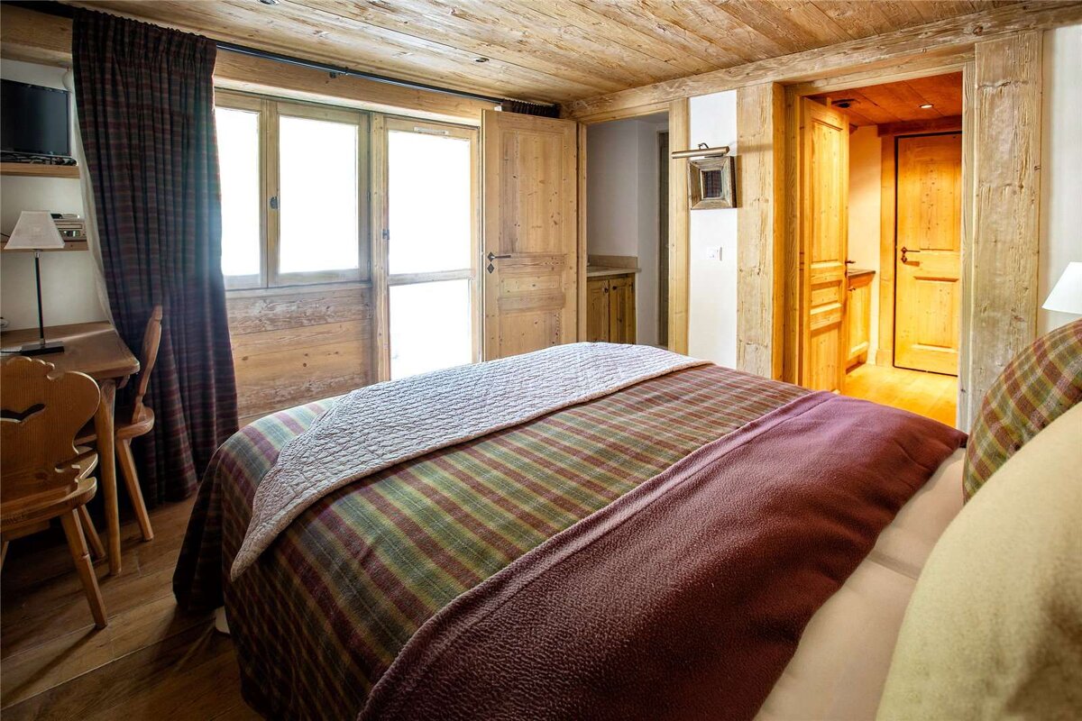 A bedroom with a bed and a desk and chairs