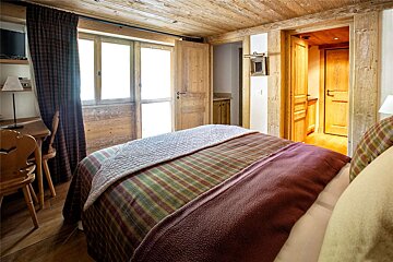 A bedroom with a bed and a desk and chairs