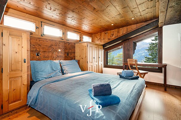 A bedroom with a bed and a window with the letter v on it
