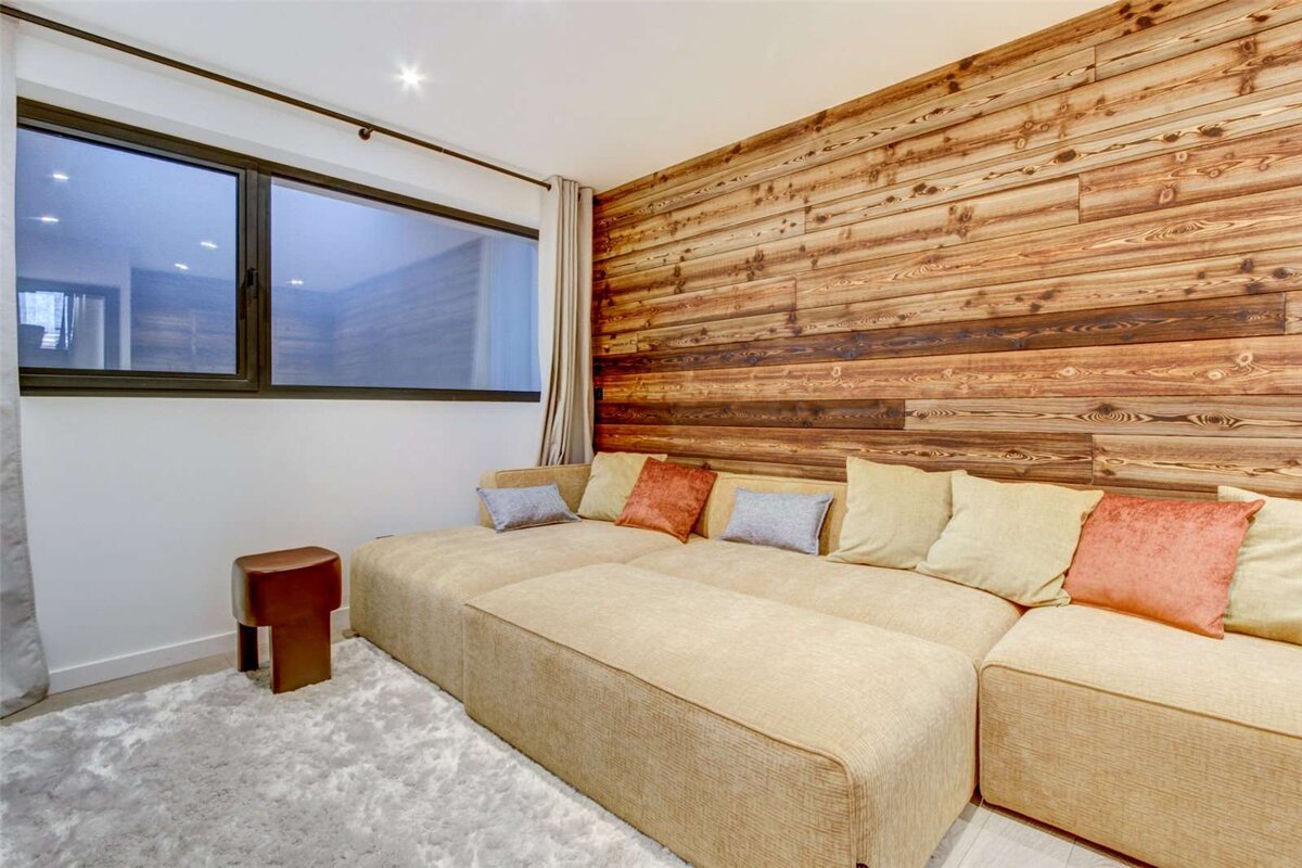 A couch in a living room with a wooden wall behind it