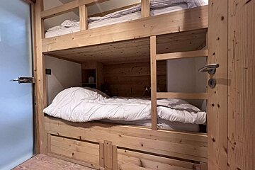 A wooden bunk bed with a white comforter on it