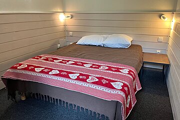 A bed with a red and white blanket with hearts on it