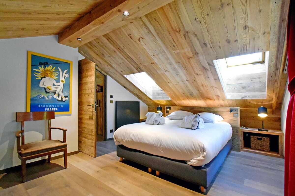 A bedroom with a bed and a chair and a poster on the wall that says ' l' alpe ' on it