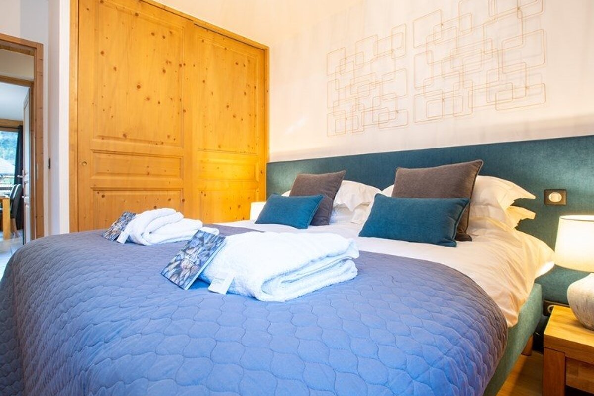 Cozy bedroom featuring a bed with blue bedding and towels, a teal headboard, and wooden sliding closet doors.