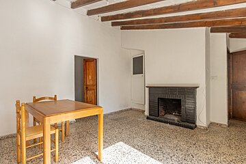 An empty room with a table and chairs and a fireplace