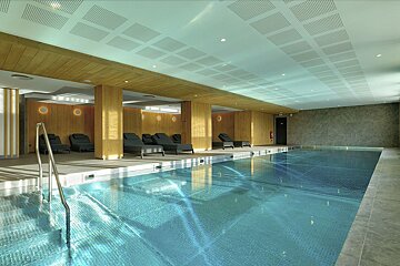 A large indoor swimming pool with chairs around it