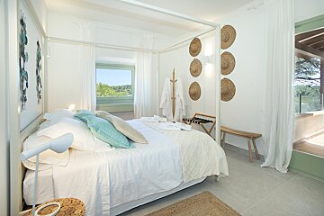 A bedroom with a canopy bed and straw hats on the wall