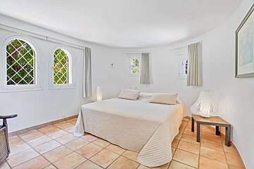 A bedroom with a large bed and two windows