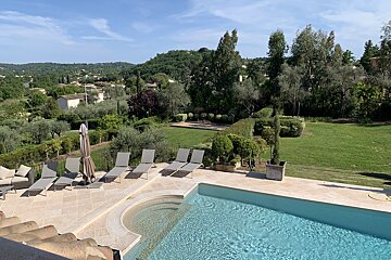 A large swimming pool surrounded by lawn chairs and umbrellas