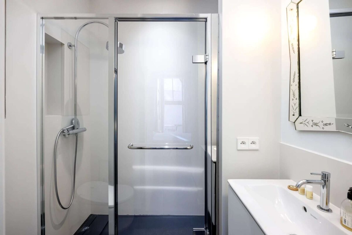 A bathroom with a glass shower door and a sink