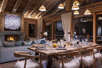 A dining room table with a bottle of wine on it